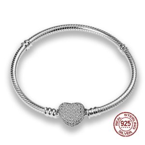Close-up of a woman's wrist with a gold chain bracelet and pearl pendant.