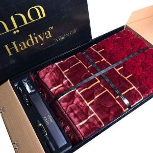 A beautiful Hadiya Classic Quilted Prayer Mat unfolded and displayed next to a closed gift box with a decorative design.