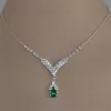Model showcasing a green gemstone necklace in a modern setting.