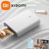Person's hand holding a small white Xiaomi Pocket Photo Printer.