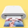 Close-up shot of a small, colorful photo with a sticky backing emerging from the Xiaomi Pocket Photo Printer.