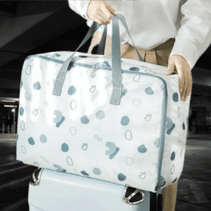 Person standing at an airport check-in counter with a large beige canvas duffel bag.