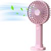 A person using a compact handheld fan outdoors on a sunny day