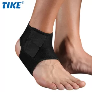 A close-up photo of a person wearing a black adjustable ankle brace with breathable mesh panels. The brace is secured with straps and conforms to the ankle and foot.