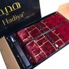 A beautiful Hadiya Classic Quilted Prayer Mat unfolded and displayed next to a closed gift box with a decorative design.