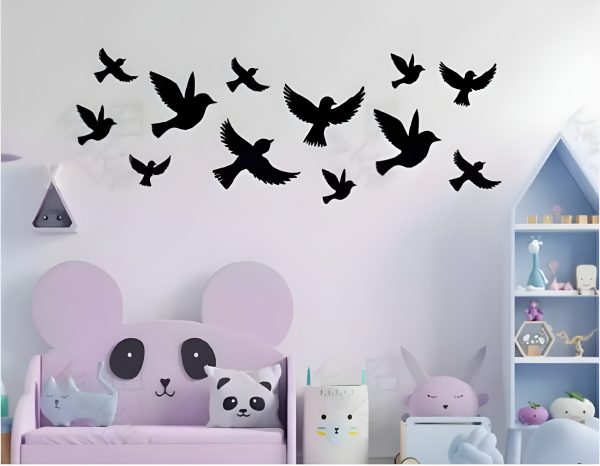 A flock of wooden birds in various shapes and sizes gracefully flies across a white wall.