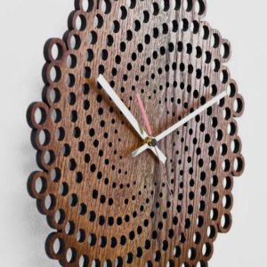 A modern spiral wood wall clock hangs on a white wall, casting a soft shadow.