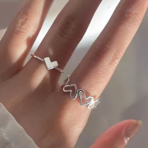 Close-up photo of the silver couple rings set. The woman's ring features a heart shape, while the man's ring features a butterfly design. Both rings have a polished silver finish.