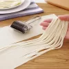 Close-up of a hand rolling out dough with a stainless steel dough roller.