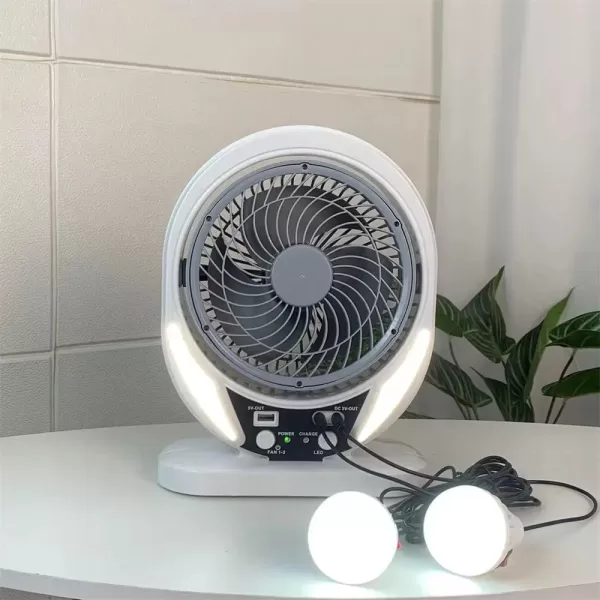 A portable solar table fan sits on a picnic table outdoors, keeping people cool on a sunny day.