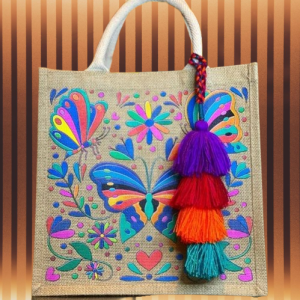 Person holding a reusable canvas tote bag with a colorful geometric pattern, handmade by an artisan.