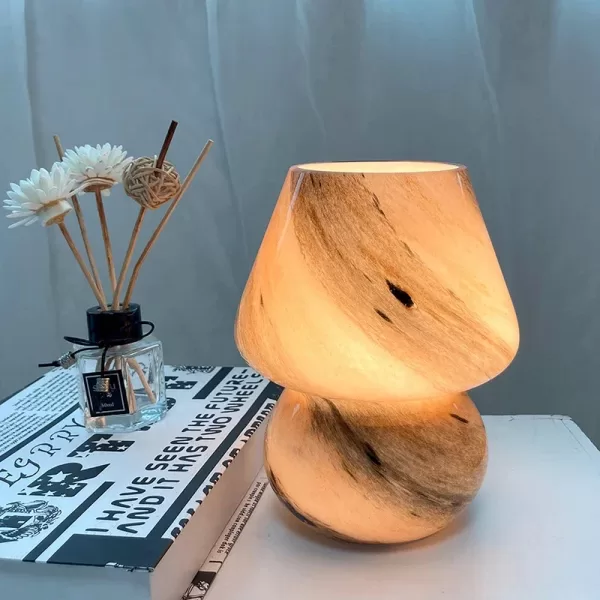 Modern glass mushroom table lamp on a side table next to a couch in a living room.