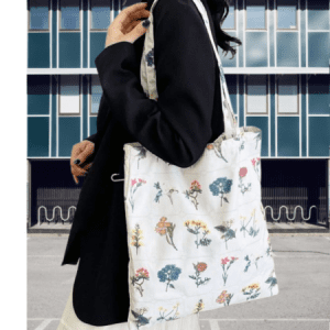 Person holding a reusable canvas tote bag filled with fresh fruits and vegetables.