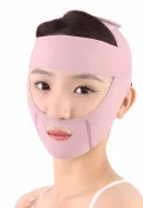 Front view of a pink face lifting band worn by a woman, covering the forehead, cheeks, and chin with an oval mouth cutout, ear openings, and small ventilation holes along the chin.