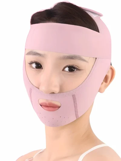 Front view of a pink face lifting band worn by a woman, covering the forehead, cheeks, and chin with an oval mouth cutout, ear openings, and small ventilation holes along the chin.