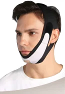 Side angle shot of a man wearing a black and white V-line face slimming chin strap showing the ear cutouts and adjustable velcro straps wrapped around the head.