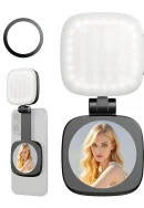 A square illuminated LED fill light with side control buttons attached to a black hinge mount with a built-in circular selfie mirror shown mounted on a smartphone, along with a separate black magnetic ring.