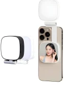 White and black portable LED selfie light featuring a square rounded design with a foldable hinge mount, built-in mini mirror displaying a reflection, attached to the back of a smartphone.