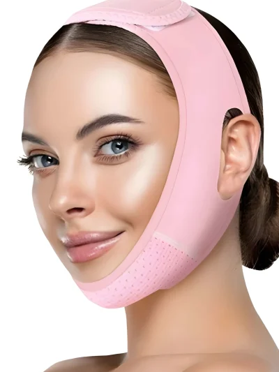 Woman wearing a pink V-line face slimming strap wrapped around her chin, cheeks, and top of the head with ear openings and perforated chin fabric design.