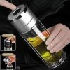 Glass tea infuser bottle with double-wall insulation and removable strainer. Person opening a modern glass tea infuser bottle filled with yellow liquid. Stainless steel and glass tea tumbler for loose leaf tea. Portable tea infuser for on-the-go brewing.