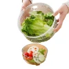 Hands holding a salad spinner basket filled with romaine lettuce over a glass bowl with salad ingredients.
