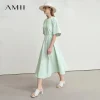Model wearing AMII backless summer office dress in light color, standing in office environment (4).