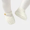 Infant wearing soft knit shoes baby girl prewalker on an indoor floor (2).