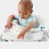 Smiling baby sitting in a Fisher-Price Sit-Me-Up Chair with snack tray on a colorful floor (1).