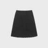 Woman wearing a dark jacquard pleated skirt in spring outdoor setting (3).