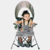 Baby chair seated in a grey portable chair with sun canopy, designed for indoor and outdoor use (1).